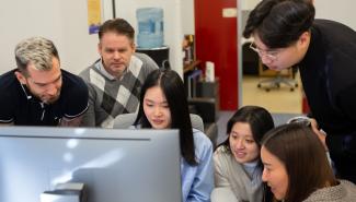 6 individuals gathered around a computer